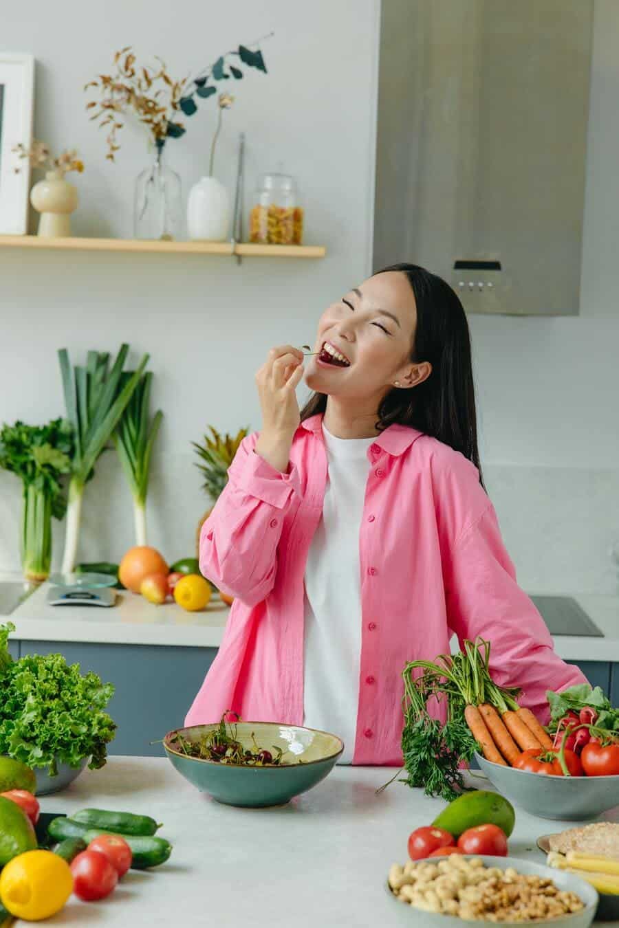 Girl eating at a table with fruits and vegetables.