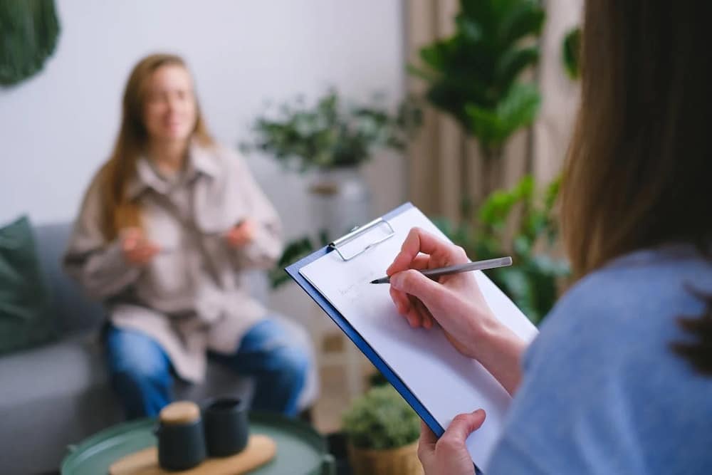 terapeuta escribiendo mientras habla con paciente